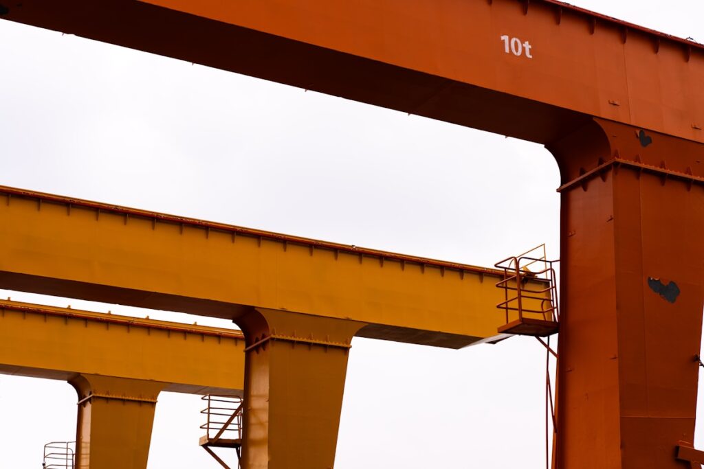 Orange and yellow industrial gantry cranes against sky
