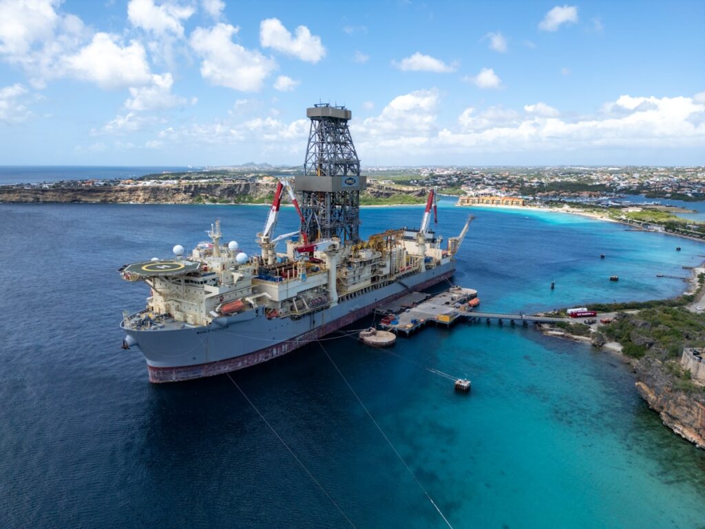 A large ship is docked in a scenic blue bay.