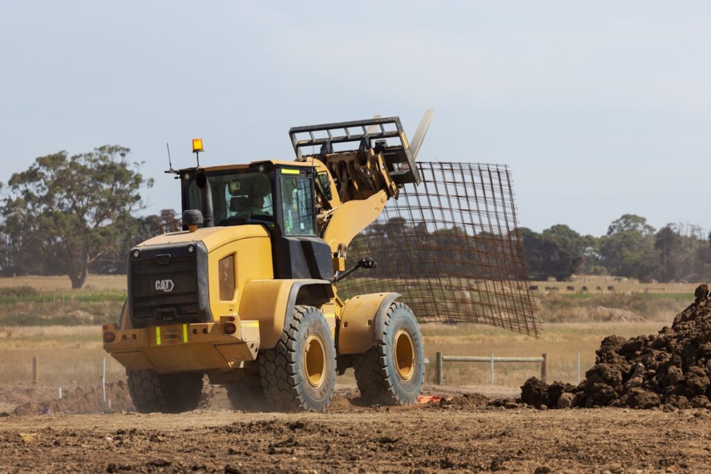 a large yellow construction vehicle driving down a dirt road