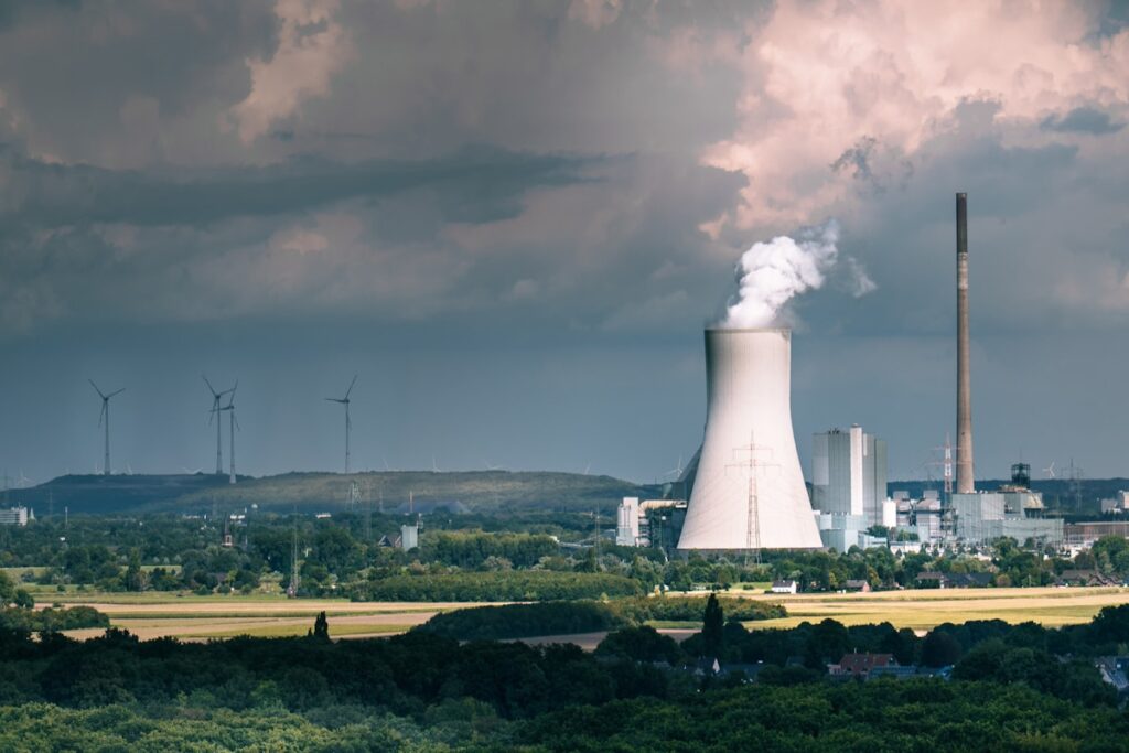 Industrial power plant with cooling tower emitting steam.