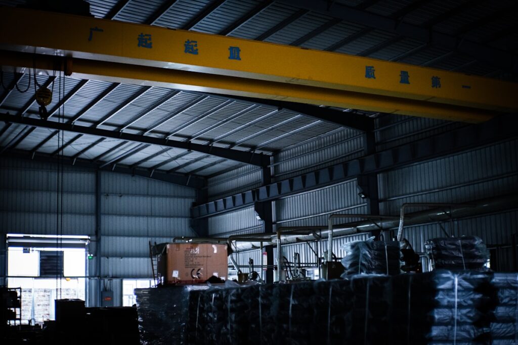 A large crane in a warehouse with lots of pallets