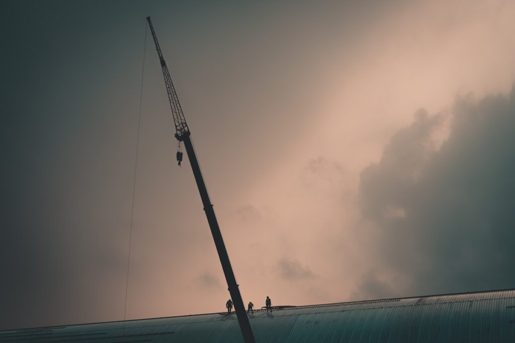 Workers on a high structure against a cloudy sky
