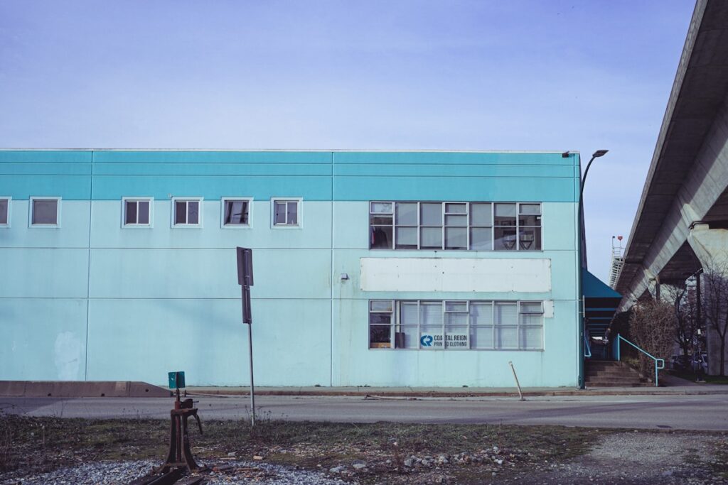 a blue building sitting next to a road under a bridge