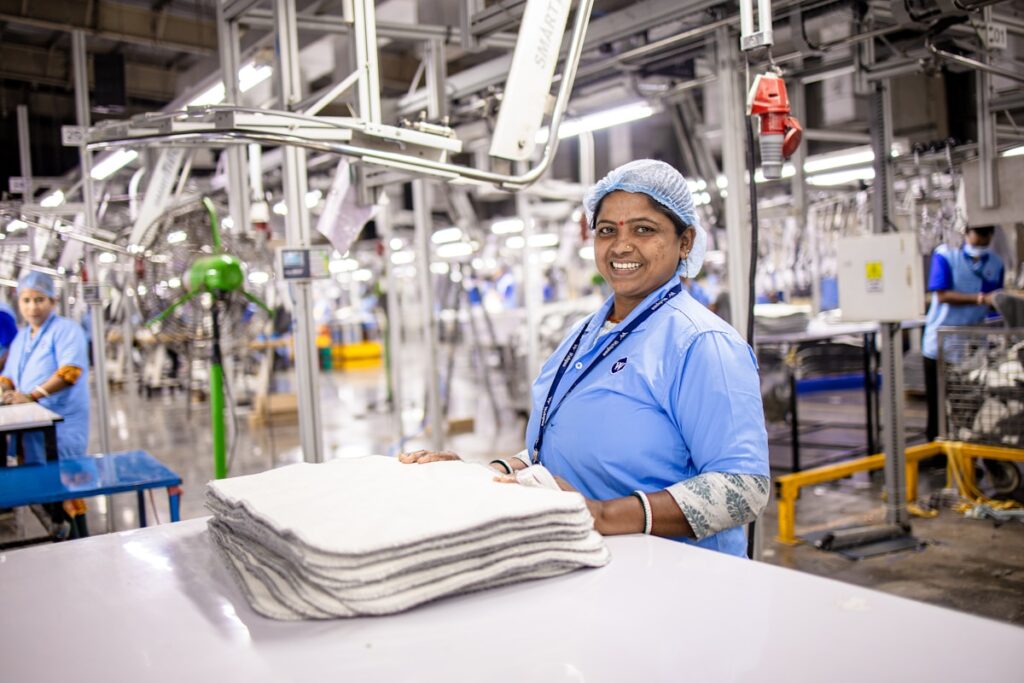 Smiling worker poses at a factory workstation.