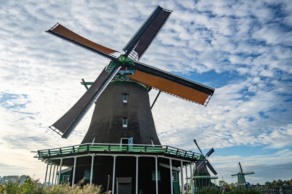 Two traditional windmills against a cloudy blue sky.