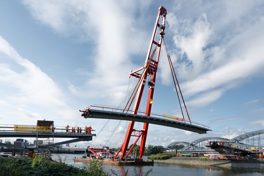Crane lifting bridge section over water